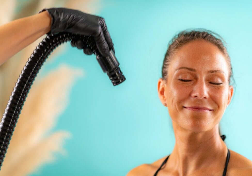 Smiling woman receiving spray tan treatment
